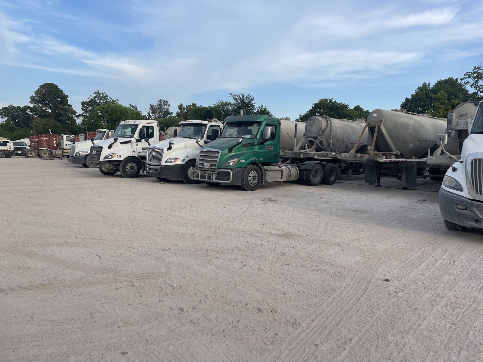 A row of tractors and pneumatic cement tankers parked side by side at the Eazy Trans yard in Houston, Texas